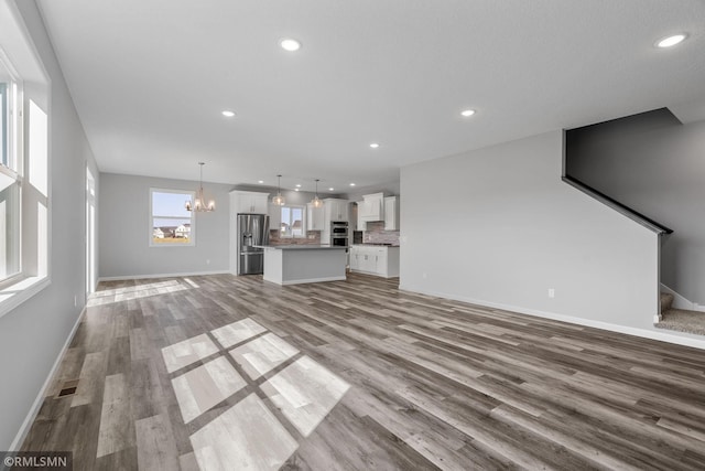 17205 61st St NE, Otsego, MN 55330 - unfurnished living room with a chandelier, wood finished floors, recessed lighting, and stairs