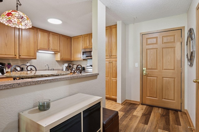 1600 Arundel St Unit 201, Saint Paul, MN 55117 - kitchen with stainless steel microwave, stove, wood finished floors, decorative backsplash, and light countertops