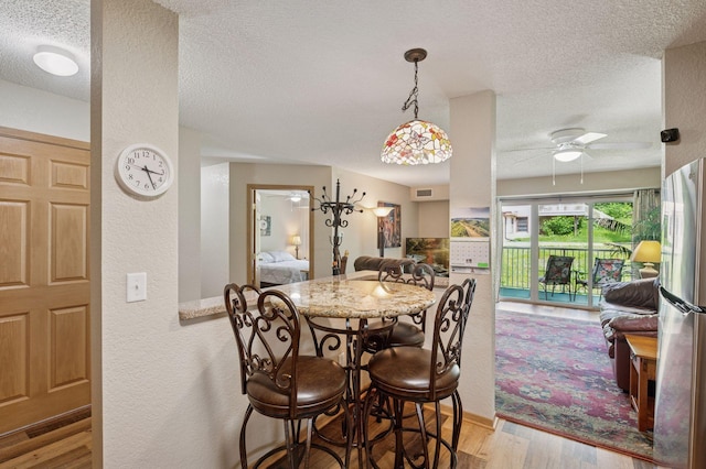1600 Arundel St Unit 201, Saint Paul, MN 55117 - dining space featuring a textured ceiling, a textured wall, light wood-style flooring, and a ceiling fan