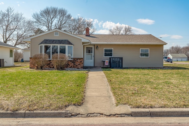 522 1st St SE, Madelia, MN 56062 - view of front of property with a front yard, a chimney, brick siding, and roof with shingles
