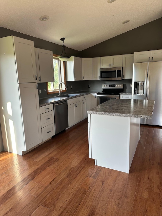 2460 Fox Hollow Ln, Owatonna, MN 55060 - kitchen with appliances with stainless steel finishes, lofted ceiling, dark wood finished floors, a kitchen island, and white cabinets