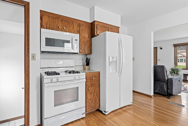 3836 Buchanan St NE, Columbia Heights, MN 55421 - kitchen featuring white appliances, light wood finished floors, brown cabinets, and light countertops