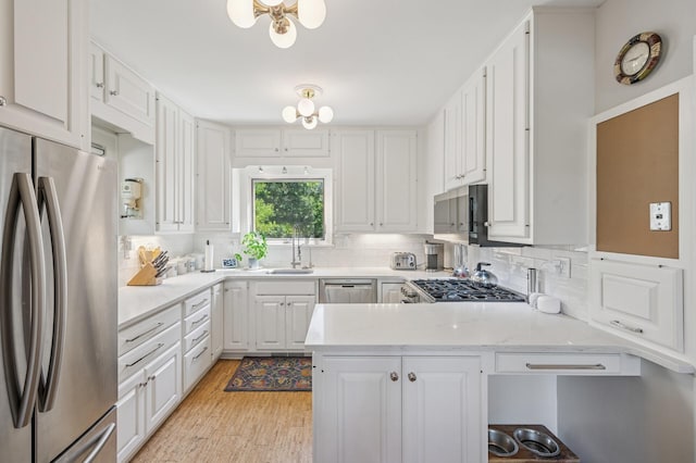 129 50th St, Minneapolis, MN 55419 - kitchen with appliances with stainless steel finishes, decorative backsplash, a peninsula, white cabinetry, and light wood finished floors