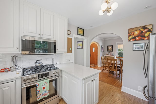 129 50th St, Minneapolis, MN 55419 - kitchen with stainless steel appliances, arched walkways, backsplash, and white cabinets