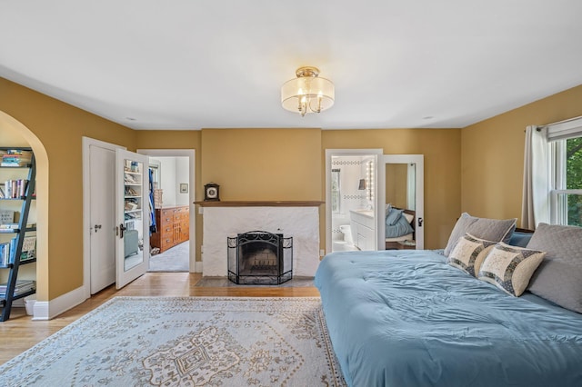 129 50th St, Minneapolis, MN 55419 - bedroom with light wood-type flooring, french doors, connected bathroom, a chandelier, and arched walkways