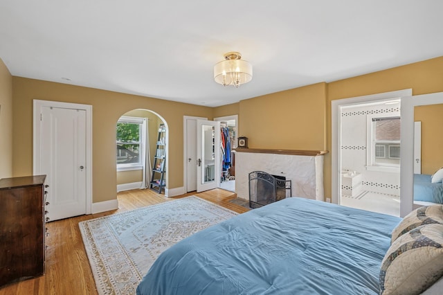 129 50th St, Minneapolis, MN 55419 - bedroom featuring arched walkways, wood finished floors, a chandelier, a fireplace, and connected bathroom