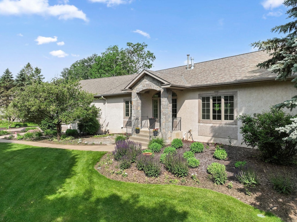 4011 114th Ln NE, Blaine, MN 55449 - view of front facade featuring stucco siding, a front yard, stone siding, and a shingled roof
