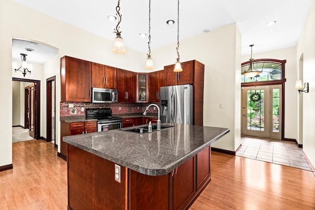 5110 Foxborrow Dr, Hermantown, MN 55811 - kitchen featuring appliances with stainless steel finishes, arched walkways, light wood-style floors, tasteful backsplash, and hanging light fixtures