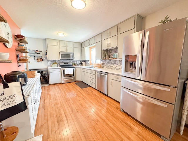 23336 County Highway 120, Fergus Falls, MN 56537 - kitchen featuring stainless steel appliances, light countertops, backsplash, light wood-style floors, and a textured ceiling