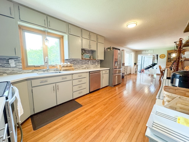23336 County Highway 120, Fergus Falls, MN 56537 - kitchen with appliances with stainless steel finishes, light countertops, decorative backsplash, a textured ceiling, and light wood-type flooring