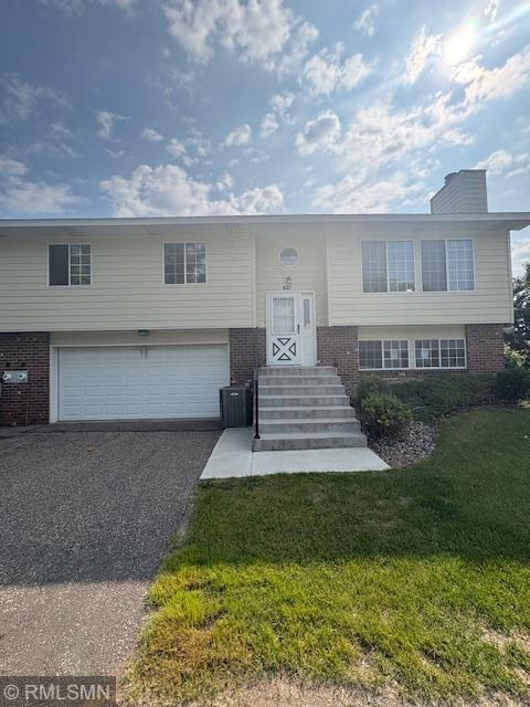 421 Dorland Rd S, Maplewood, MN 55119 - bi-level home with brick siding, a garage, a front lawn, and asphalt driveway