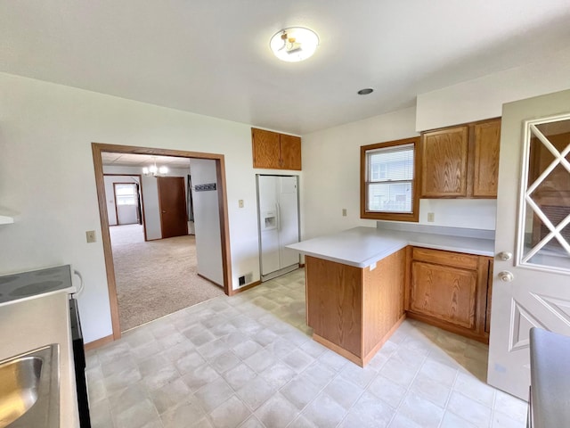 212 Sanborn St, Springfield, MN 56087 - kitchen with white fridge with ice dispenser, a peninsula, brown cabinetry, a chandelier, and light countertops