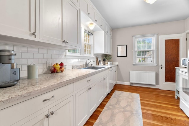 1921 James Ave, Saint Paul, MN 55105 - kitchen with radiator heating unit, backsplash, white cabinets, and light wood-type flooring