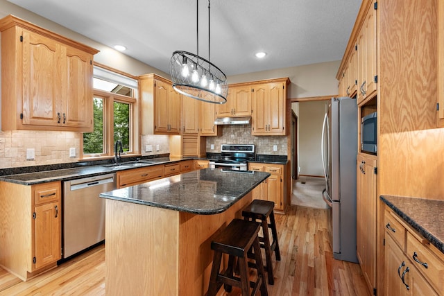 842 Vista Cir, Delano, MN 55328 - kitchen with appliances with stainless steel finishes, under cabinet range hood, light wood-type flooring, a breakfast bar, and a kitchen island