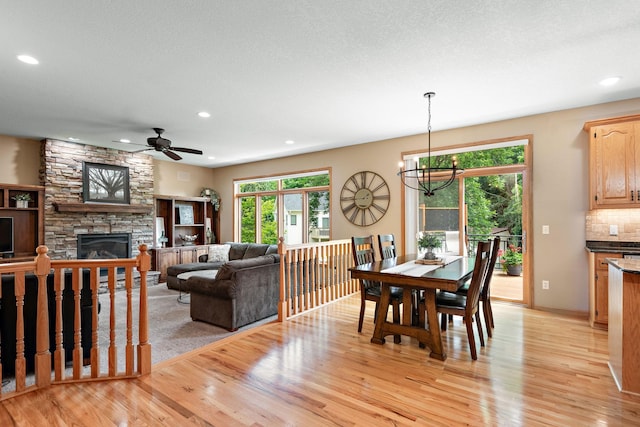 842 Vista Cir, Delano, MN 55328 - dining area with light wood finished floors, a stone fireplace, recessed lighting, ceiling fan, and a chandelier