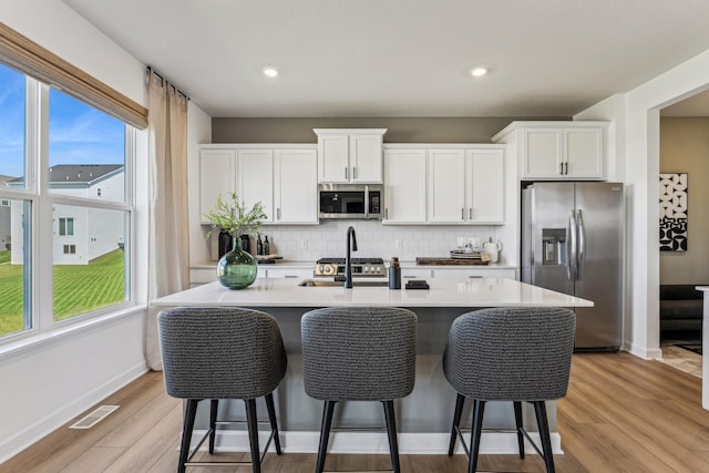 7588 Norway Ln, Lino Lakes, MN 55038 - kitchen with stainless steel appliances, an island with sink, tasteful backsplash, white cabinets, and recessed lighting