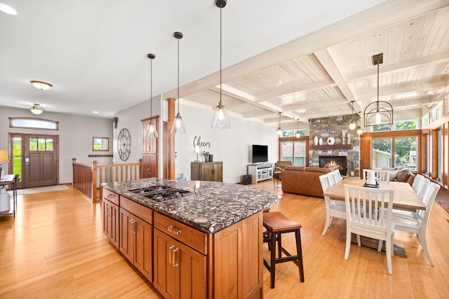 70348 219th St, Dassel, MN 55325 - kitchen featuring stainless steel gas cooktop, light wood-style flooring, a center island, beam ceiling, and dark stone countertops
