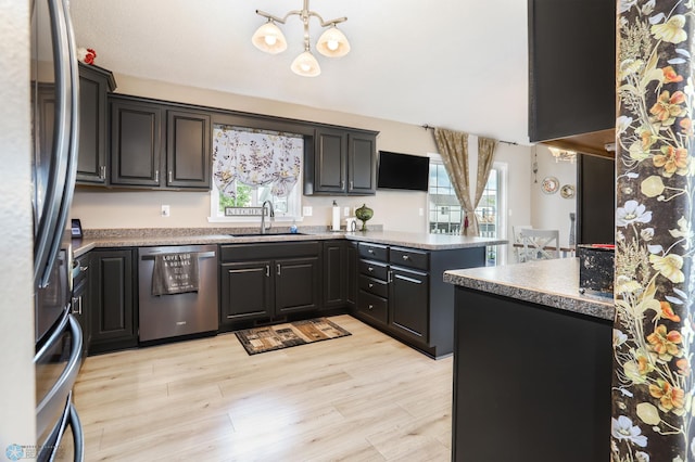 4450 48th St S, Fargo, ND 58104 - kitchen featuring stainless steel appliances, a peninsula, a chandelier, and light wood-type flooring