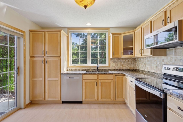 1900 Hunter Hill Rd, Hudson, WI 54016 - kitchen featuring stainless steel appliances, dark stone counters, a textured ceiling, backsplash, and light wood finished floors