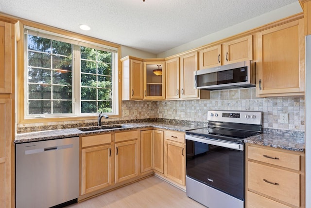 1900 Hunter Hill Rd, Hudson, WI 54016 - kitchen with appliances with stainless steel finishes, a textured ceiling, light brown cabinetry, dark stone countertops, and tasteful backsplash