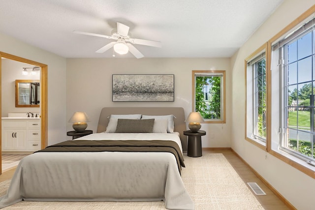 1900 Hunter Hill Rd, Hudson, WI 54016 - bedroom with multiple windows, ensuite bathroom, light wood finished floors, and ceiling fan