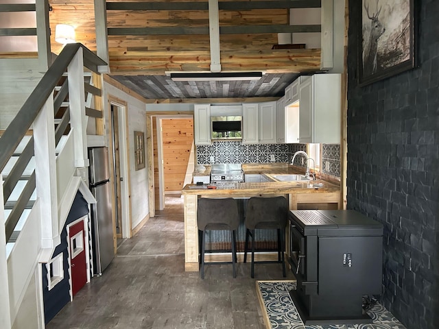 6274 Azalea Rd, Motley Twp, MN 56466 - kitchen with stainless steel appliances, white cabinetry, decorative backsplash, a peninsula, and a wooden ceiling with exposed beams