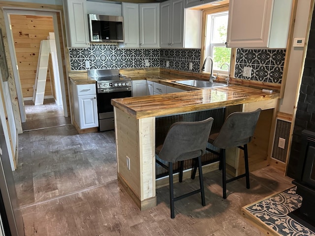 6274 Azalea Rd, Motley Twp, MN 56466 - kitchen with appliances with stainless steel finishes, butcher block counters, white cabinets, dark wood-style floors, and a peninsula