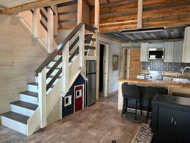 6274 Azalea Rd, Motley Twp, MN 56466 - kitchen featuring appliances with stainless steel finishes, wood finished floors, backsplash, white cabinetry, and wooden walls