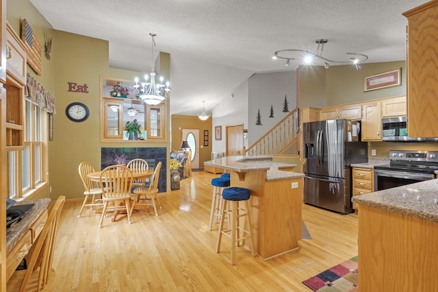 11770 N Meadow Curv, Lindstrom, MN 55045 - kitchen with stainless steel appliances, light wood-style flooring, a kitchen island, lofted ceiling, and a breakfast bar