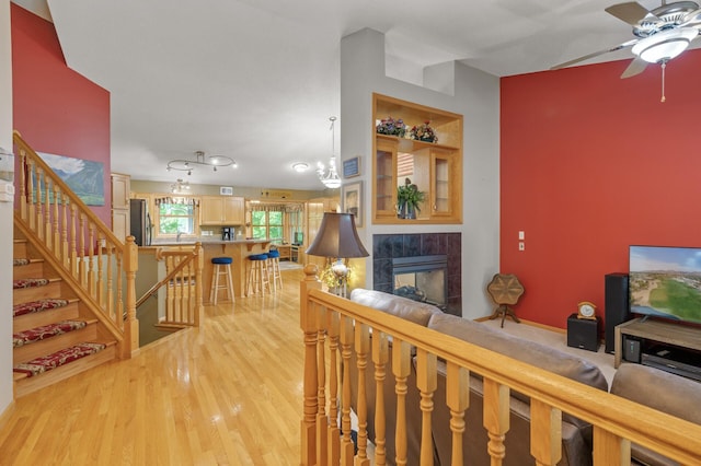 11770 N Meadow Curv, Lindstrom, MN 55045 - living room featuring a ceiling fan, a fireplace, light wood-type flooring, and stairway