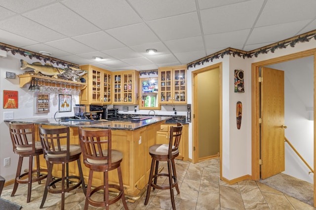 11770 N Meadow Curv, Lindstrom, MN 55045 - kitchen with a drop ceiling, a peninsula, a breakfast bar area, glass insert cabinets, and dark stone counters