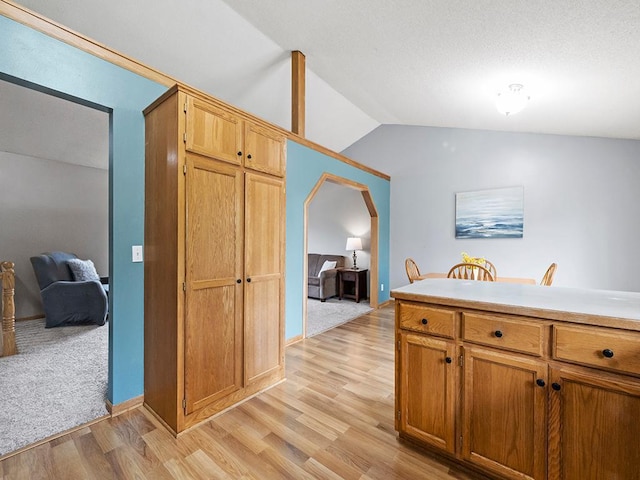 6735 378th St, North Branch, MN 55056 - kitchen featuring vaulted ceiling, light wood-type flooring, arched walkways, light countertops, and brown cabinetry
