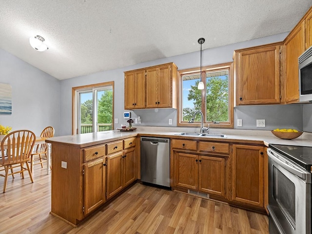 6735 378th St, North Branch, MN 55056 - kitchen featuring stainless steel appliances, a peninsula, a textured ceiling, light wood-style floors, and brown cabinetry