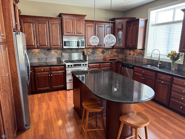 716 Northridge Way W, Fargo, ND 58078 - kitchen with appliances with stainless steel finishes, a kitchen breakfast bar, light wood finished floors, and glass insert cabinets