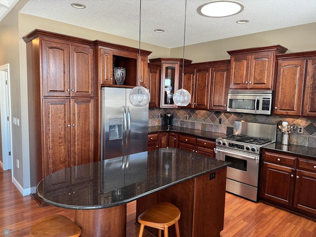 716 Northridge Way W, Fargo, ND 58078 - kitchen with stainless steel appliances, a breakfast bar, wood finished floors, a kitchen island, and a textured ceiling