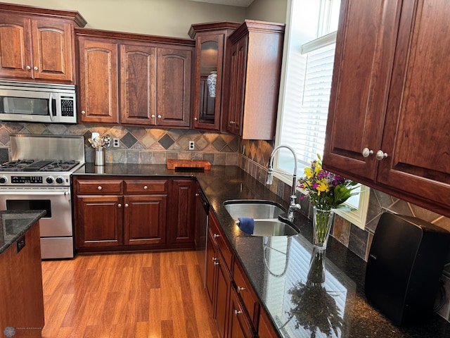 716 Northridge Way W, Fargo, ND 58078 - kitchen with stainless steel appliances, light wood-style flooring, dark stone countertops, backsplash, and glass insert cabinets