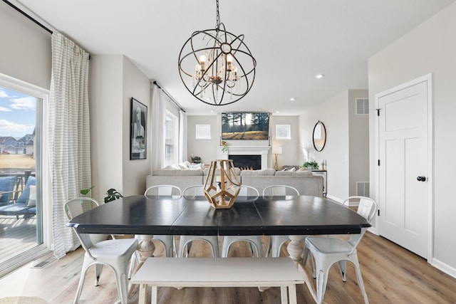 2878 Kama Ave NE, Saint Michael, MN 55376 - dining area with light wood finished floors, a chandelier, a warm lit fireplace, and recessed lighting