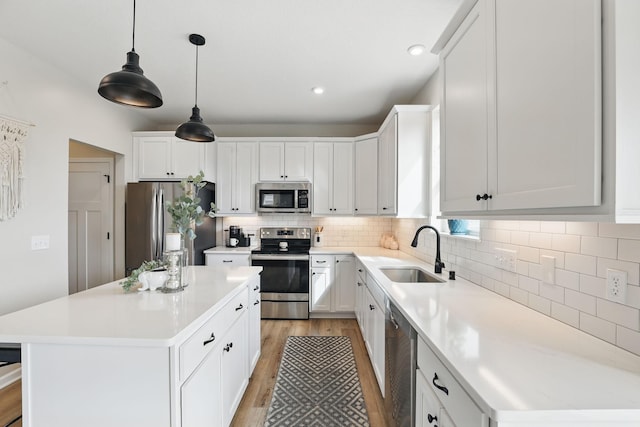 2878 Kama Ave NE, Saint Michael, MN 55376 - kitchen with appliances with stainless steel finishes, light wood-style floors, a center island, light countertops, and backsplash