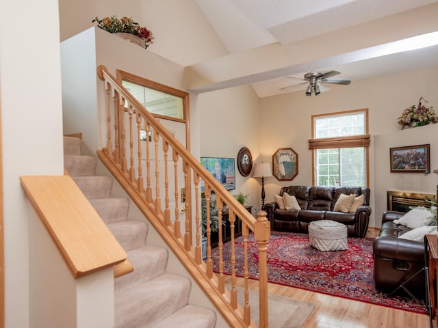 6388 Tahoe Rd, Woodbury, MN 55125 - living room featuring wood finished floors, a ceiling fan, high vaulted ceiling, and stairs