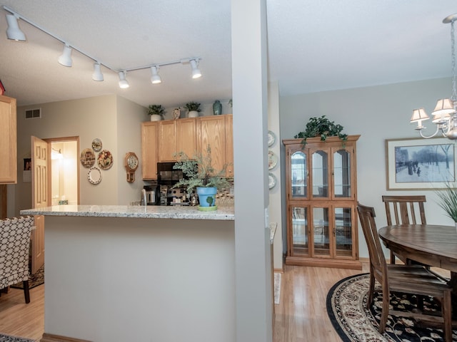 6388 Tahoe Rd, Woodbury, MN 55125 - kitchen featuring light wood finished floors, track lighting, a chandelier, a peninsula, and light stone counters