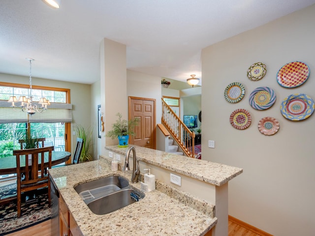 6388 Tahoe Rd, Woodbury, MN 55125 - kitchen with light wood-style flooring, a chandelier, light stone counters, and stainless steel dishwasher