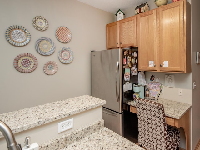 6388 Tahoe Rd, Woodbury, MN 55125 - kitchen featuring freestanding refrigerator, built in desk, and light stone counters