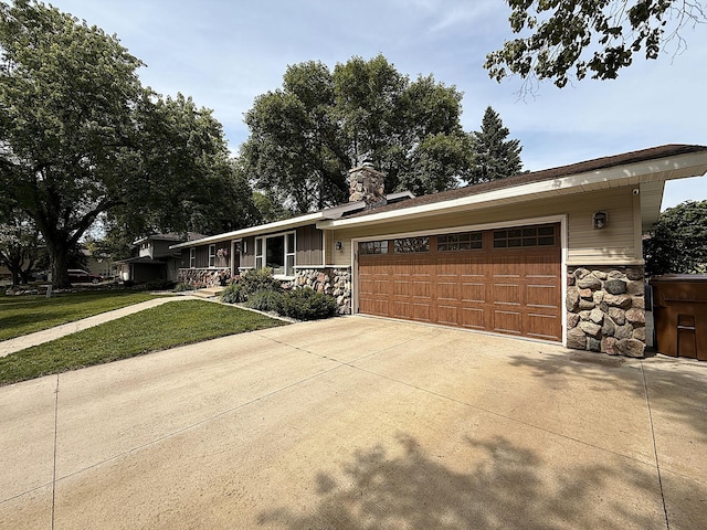 112 Orchard Cir, Montevideo, MN 56265 - view of front facade featuring stone siding, an attached garage, a front yard, driveway, and a chimney