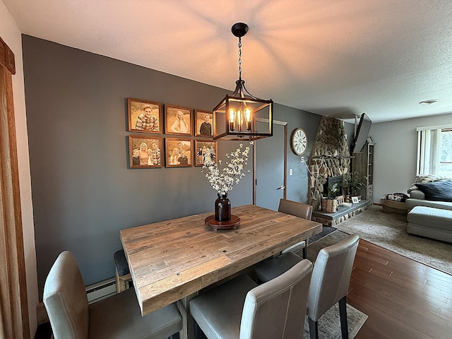 112 Orchard Cir, Montevideo, MN 56265 - dining area with a chandelier, a baseboard radiator, a textured ceiling, and dark wood-type flooring