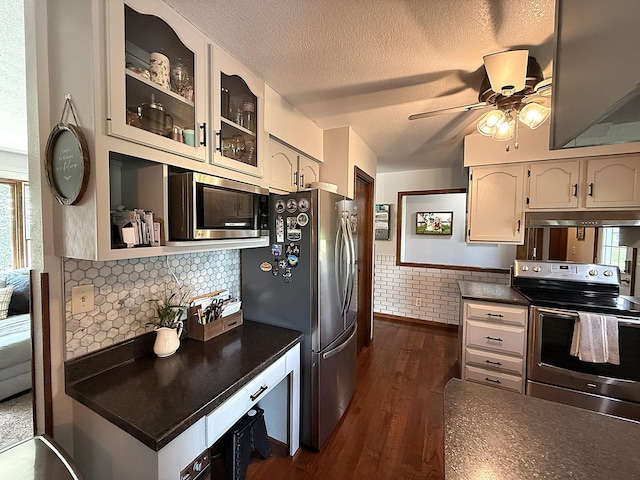 112 Orchard Cir, Montevideo, MN 56265 - kitchen featuring appliances with stainless steel finishes, under cabinet range hood, dark countertops, dark wood-style floors, and a ceiling fan
