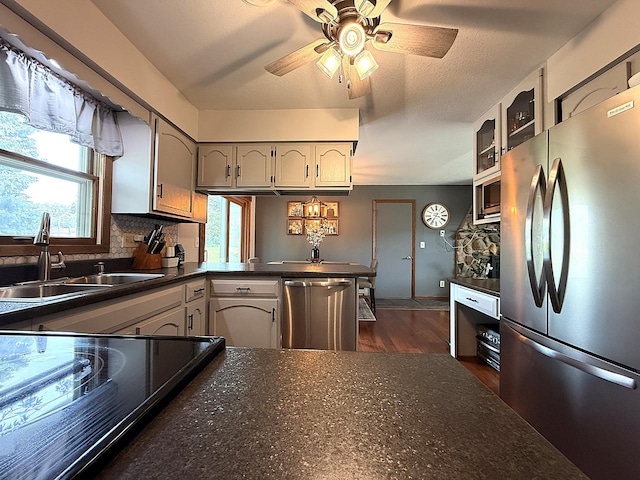112 Orchard Cir, Montevideo, MN 56265 - kitchen with stainless steel appliances, dark countertops, ceiling fan, a peninsula, and dark wood-style floors