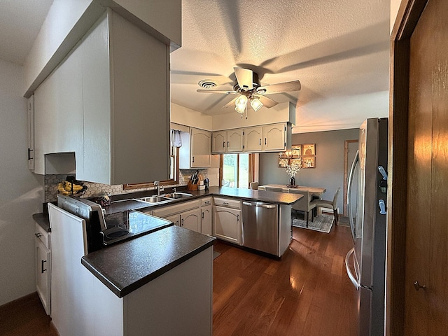 112 Orchard Cir, Montevideo, MN 56265 - kitchen with stainless steel appliances, a peninsula, dark countertops, ceiling fan, and dark wood-style flooring