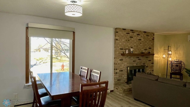 2440 15th St S Unit B14, Fargo, ND 58103 - dining room featuring light wood-style floors, a brick fireplace, and a textured ceiling