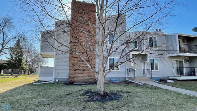 2440 15th St S Unit B14, Fargo, ND 58103 - view of side of home featuring a chimney, a lawn, and a balcony