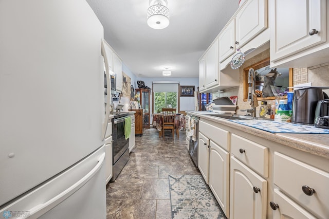 2440 15th St S Unit B14, Fargo, ND 58103 - kitchen featuring appliances with stainless steel finishes, stone finish floors, tasteful backsplash, light countertops, and white cabinetry